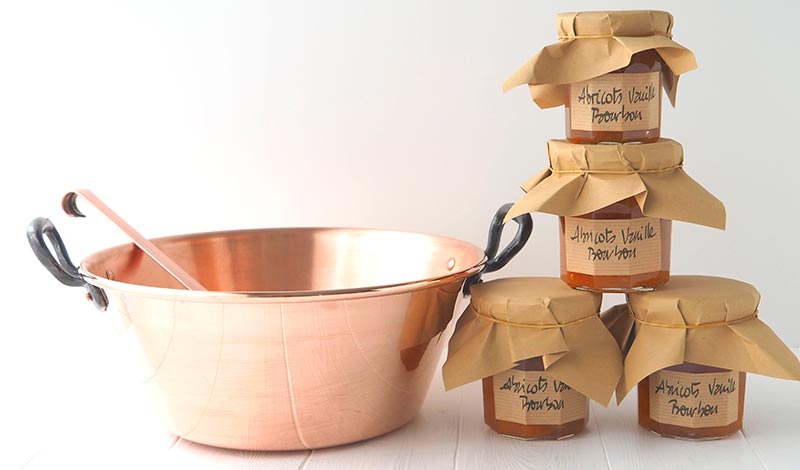 Bassine en cuivre et pots empilés La bassine à confiture en cuivre avec ses pots de confiture d'abricots