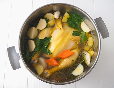 La cuisson de la poule au pot dans son bouillon au milieu des légumes