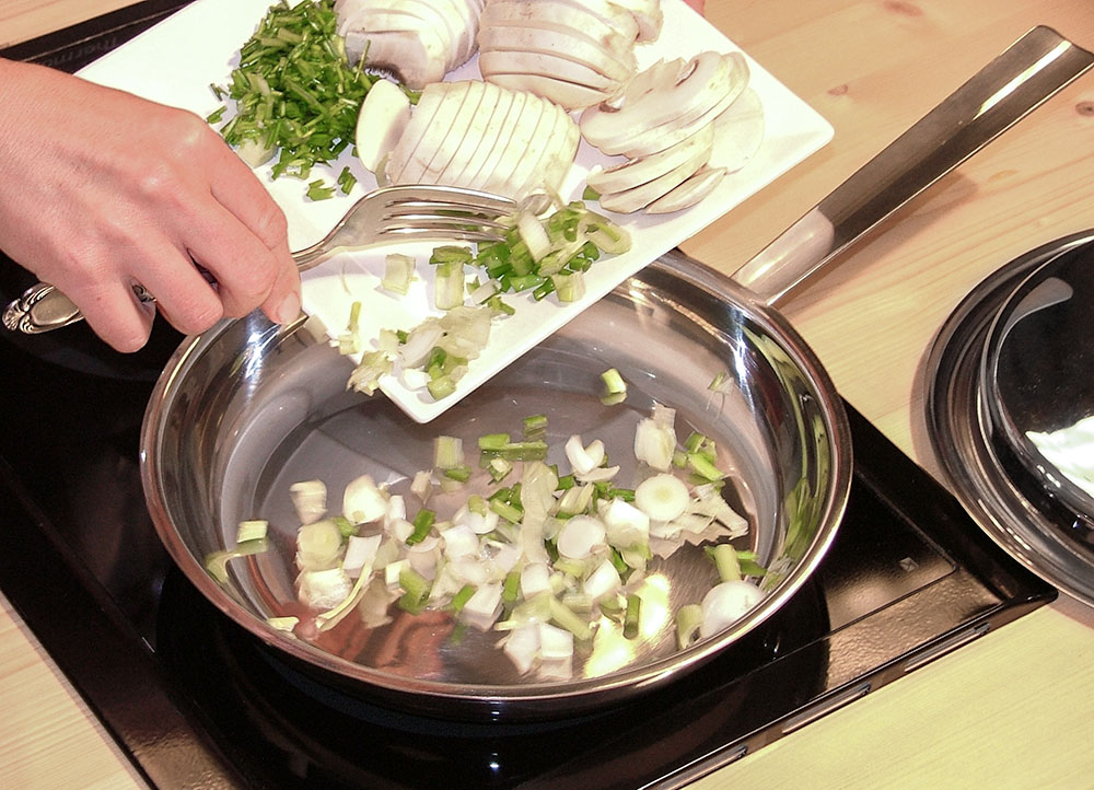 Préparation d'un repas : cuisson des champignons dans la poêle à frire